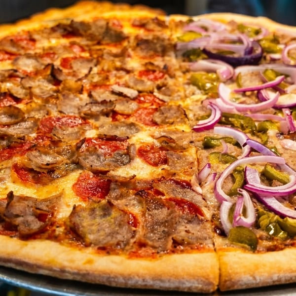 A large pizza with half pepperoni and sausage, and half green peppers and red onions.